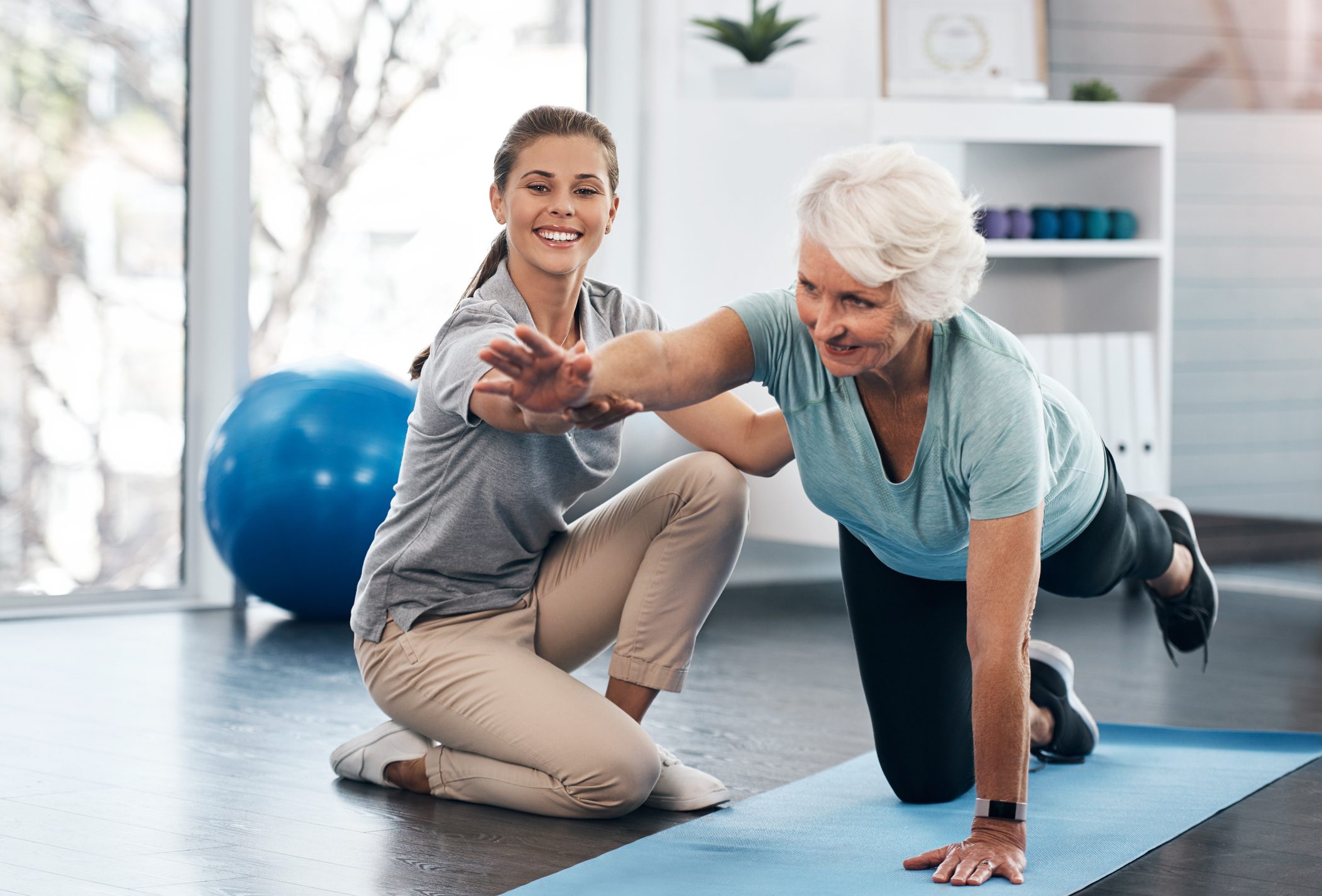 Elderly woman doing yoga with assistance